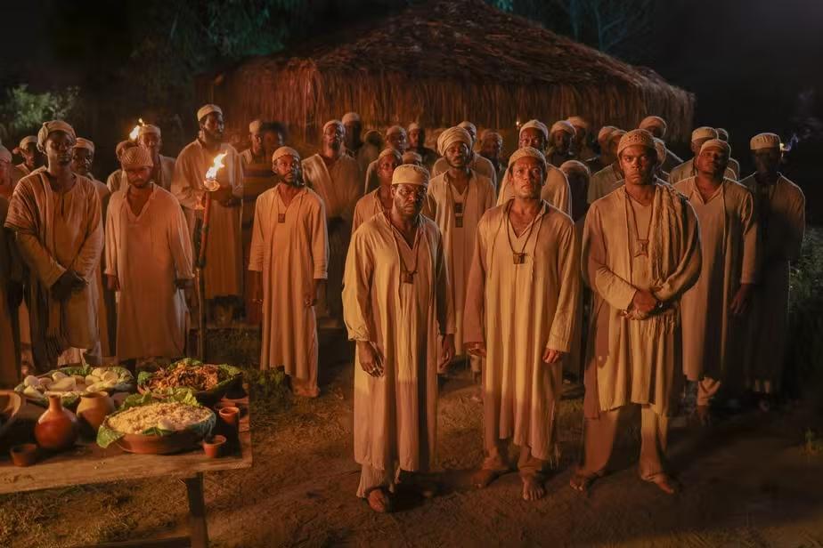 Um grupo de homens negros usando roupas brancas e colares.